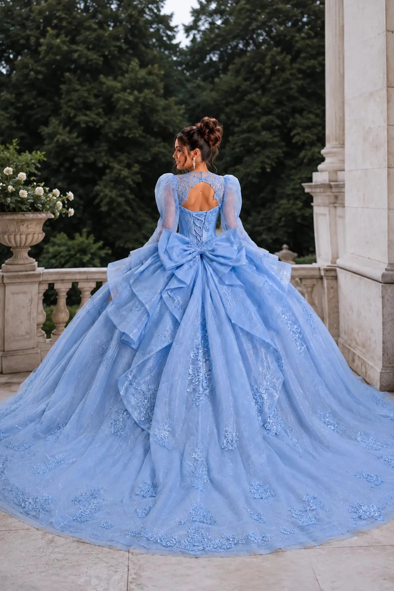 Back view of a woman wearing bahama blue quinceañera dress featuring corset back design, tiered ruffle skirt, and glitter tulle