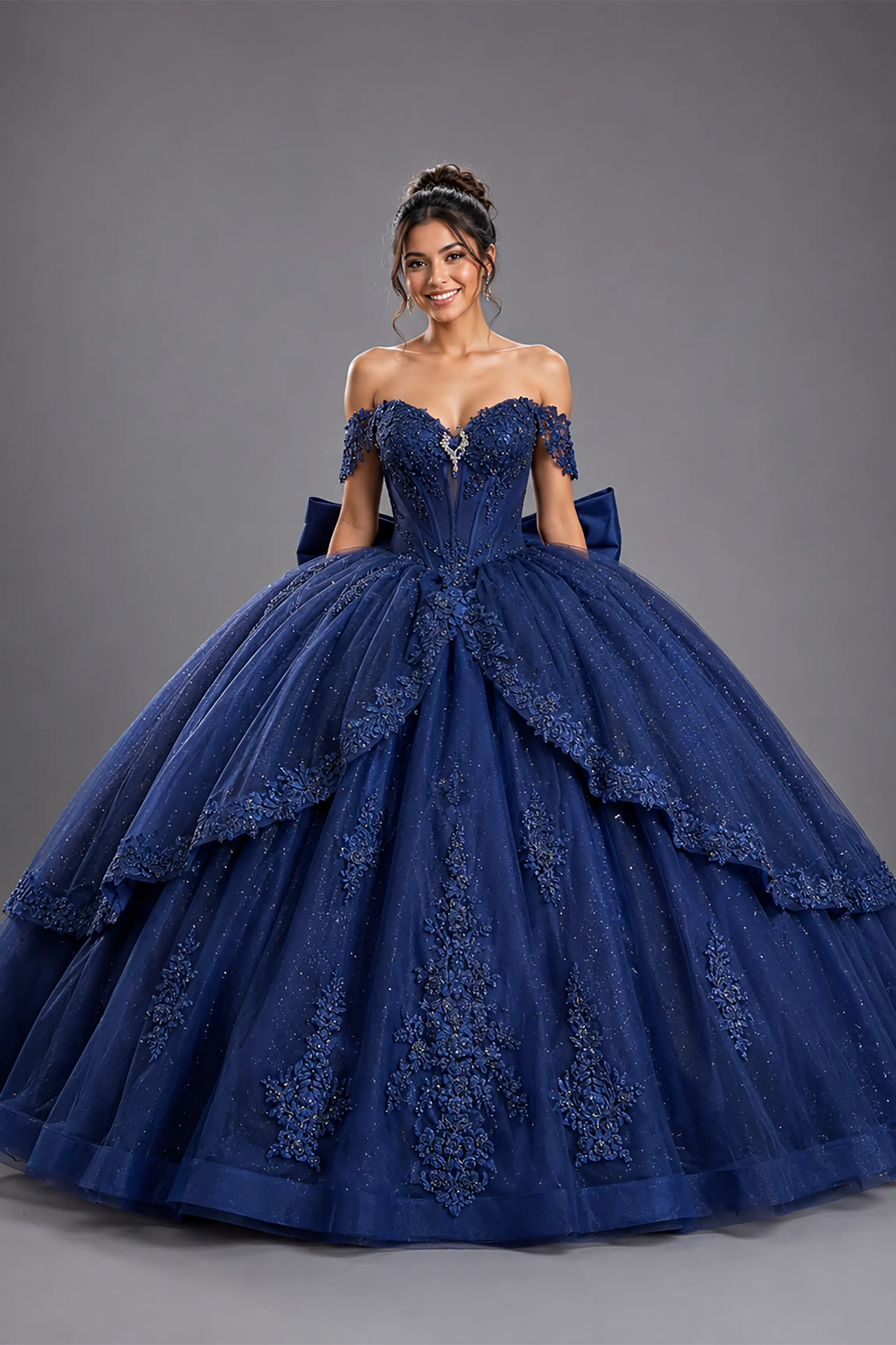 Front view of a woman wearing navy quinceañera dress featuring floral embroidery, tiered overskirt, corset bodice, and glitter tulle