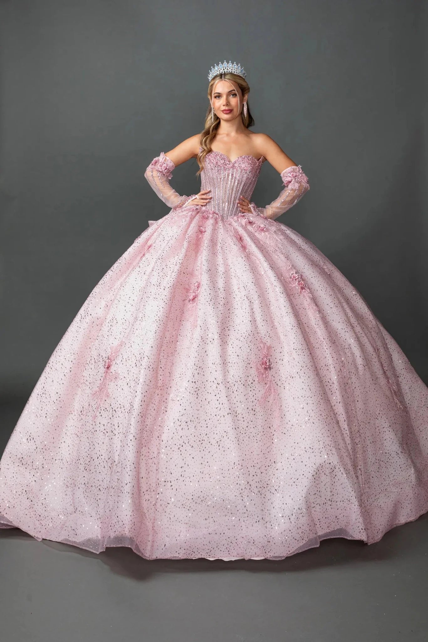 Front view of a woman wearing blush quinceañera, strapless, floral appliques, glitter tulle skirt, detachable gloves