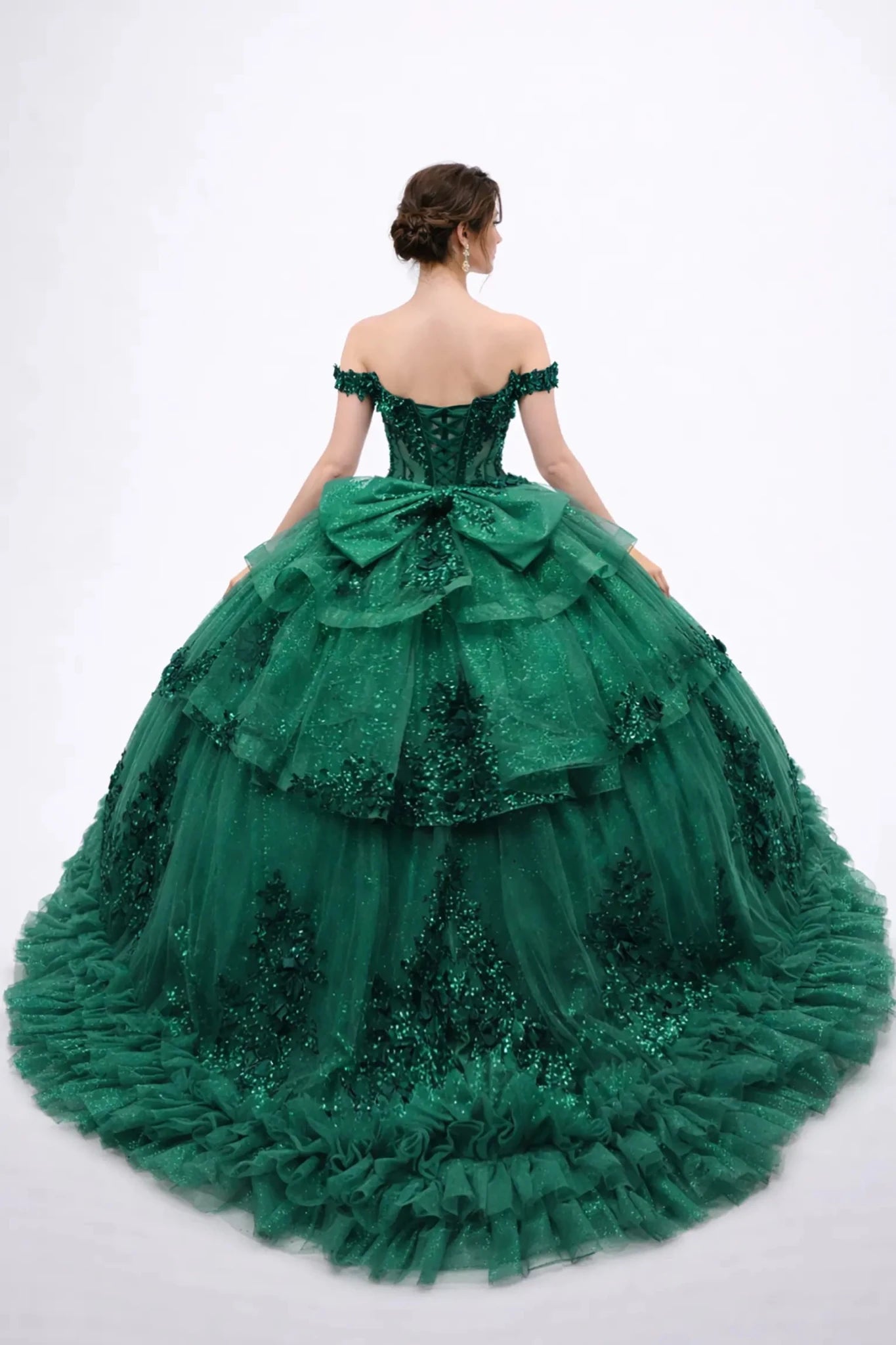 Back view of a woman wearing hunter green quinceañera, lace-up, tiered tulle, floral appliques, off-shoulder sleeves