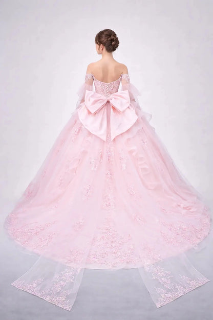 Woman standing back-facing in blush ball gown with lace-up corset bodice, embellished detailing, and cascading full skirt

