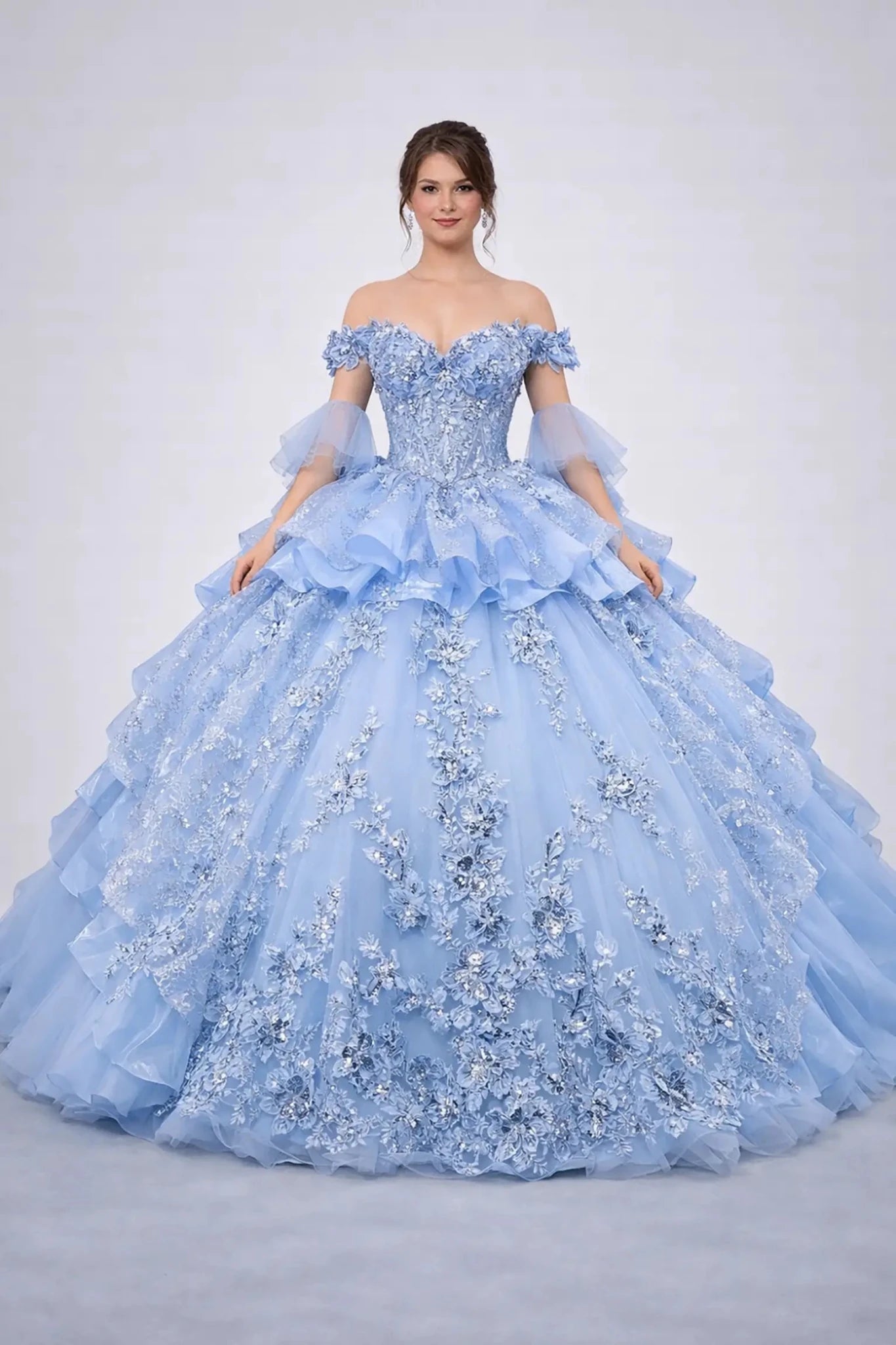 Woman standing front-facing in elegant Bahama blue ball gown with floral appliqué bodice, glitter tulle skirt, and voluminous layered silhouette