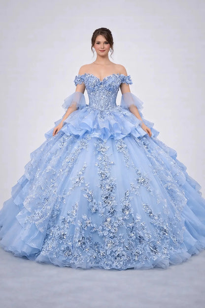 Woman standing front-facing in elegant Bahama blue ball gown with floral appliqué bodice, glitter tulle skirt, and voluminous layered silhouette