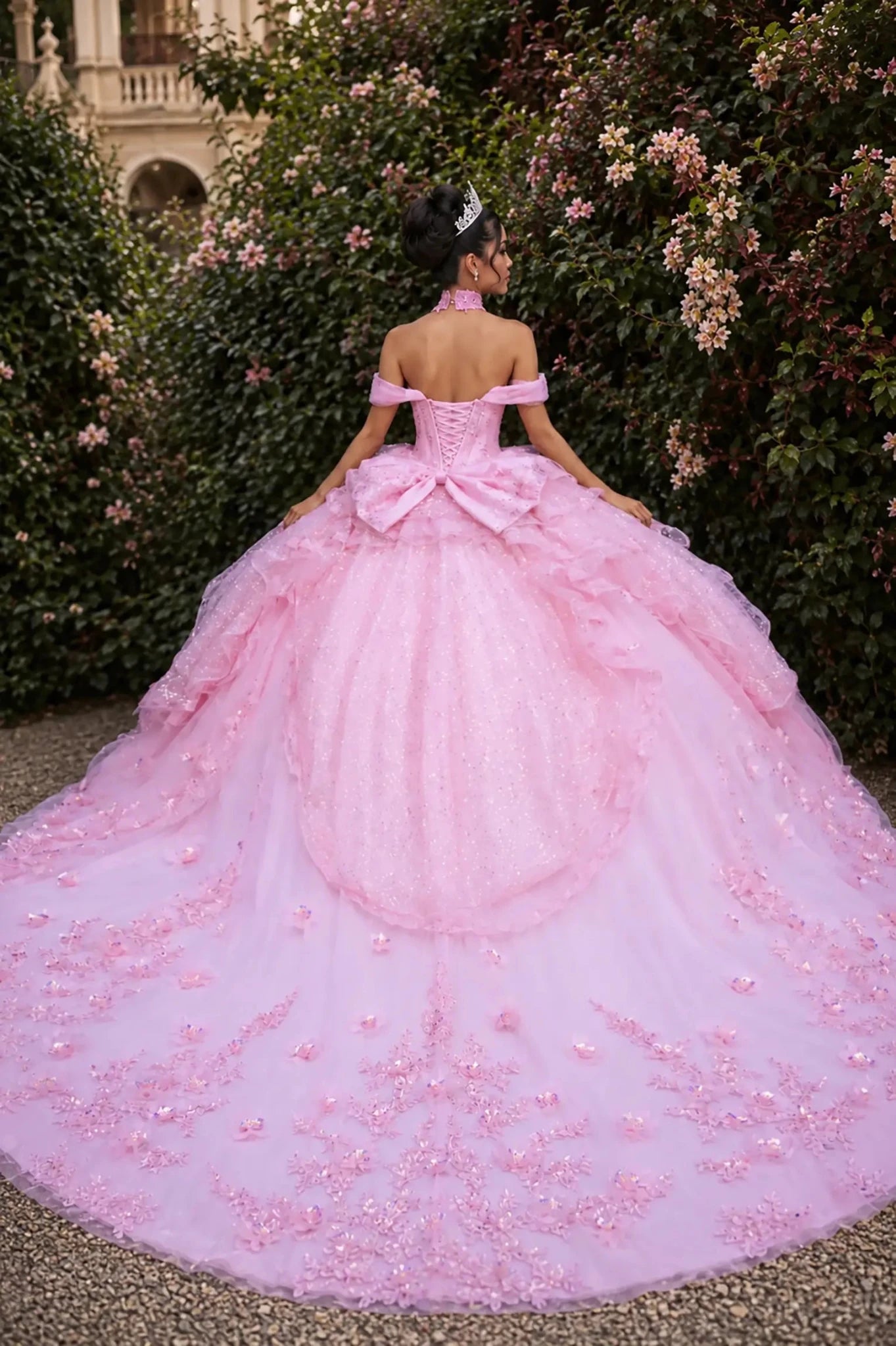 Back view of a woman wearing pink quinceañera, lace-up, ruffle tulle layers, floral appliques, off-shoulder sleeves