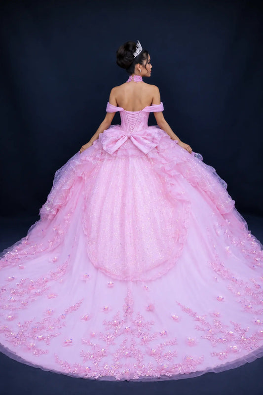 Full back view of a woman wearing a pink quinceañera gown with lace-up corset back, cascading ruffle tulle layers, floral applique accents, and off-shoulder sleeves