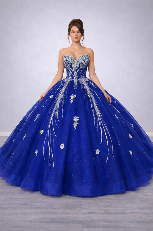 Woman standing front-facing in elegant royal blue ball gown with beaded corset bodice and voluminous layered tulle skirt