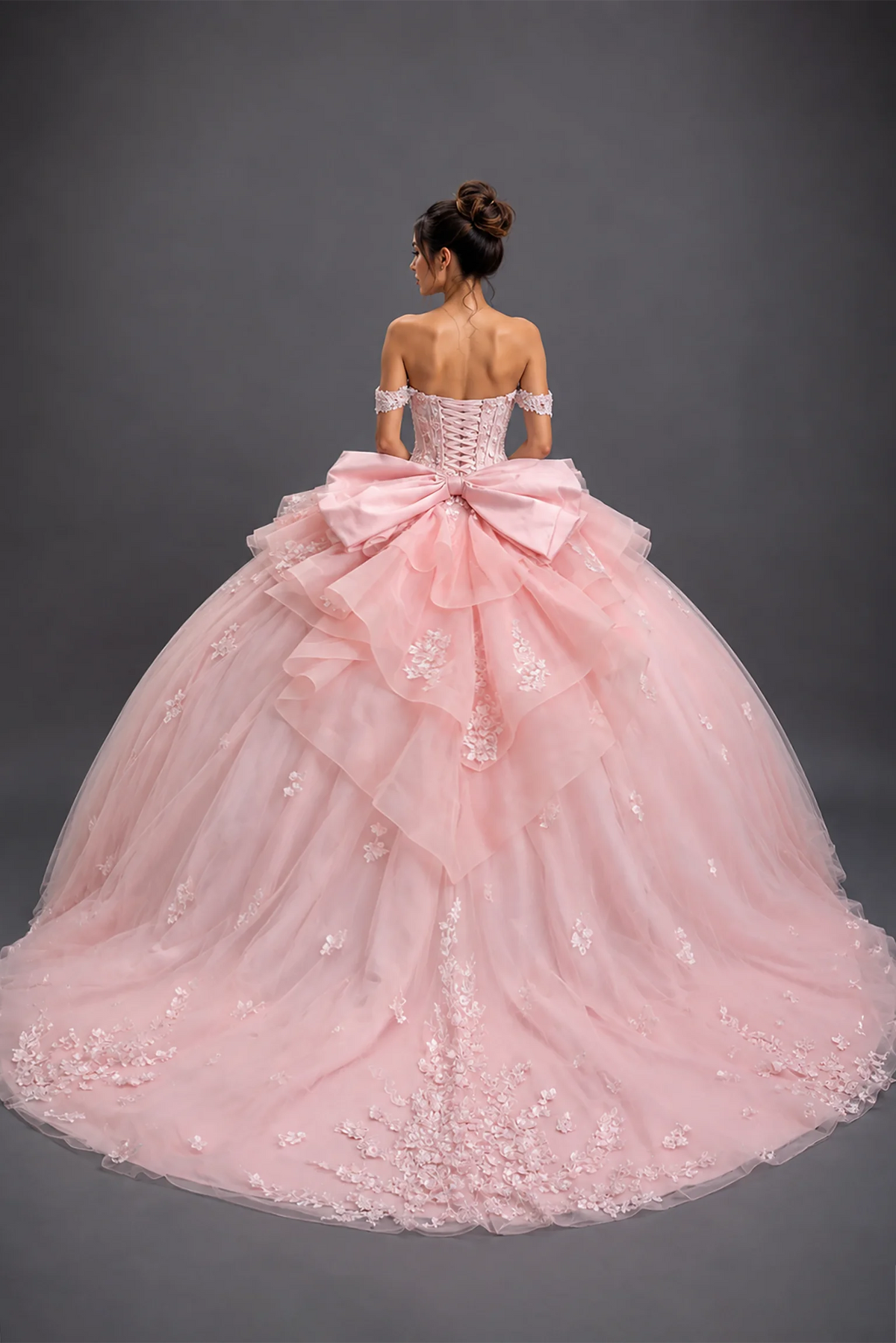 Back view of blush quinceañera dress with lace-up corset, bow and floral tulle train