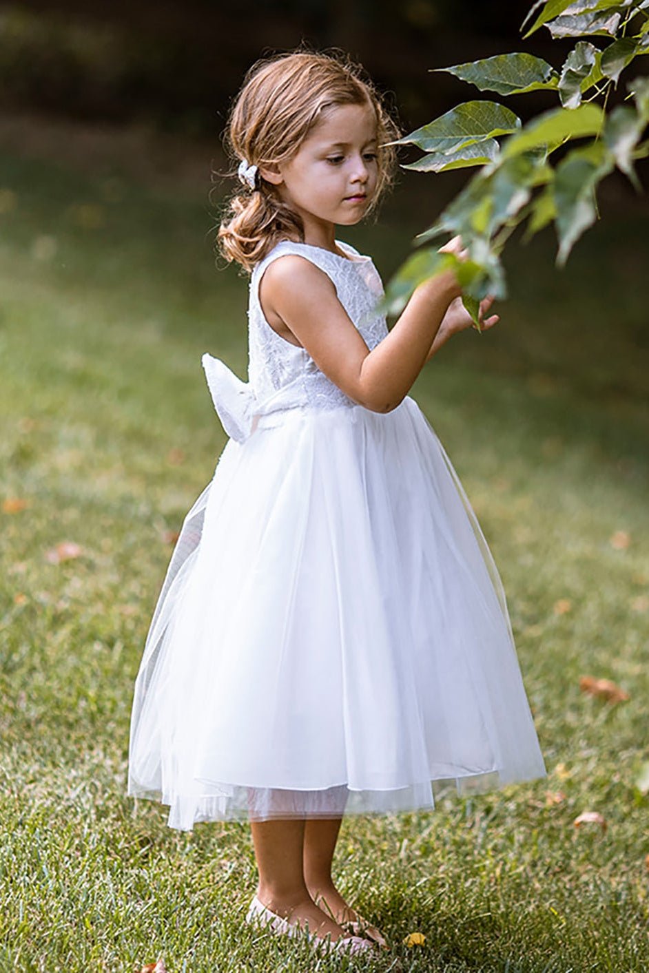 Sleeveless lace tulle flower girl dress with sequin bodice, V-back design, and shimmering tulle skirt.
