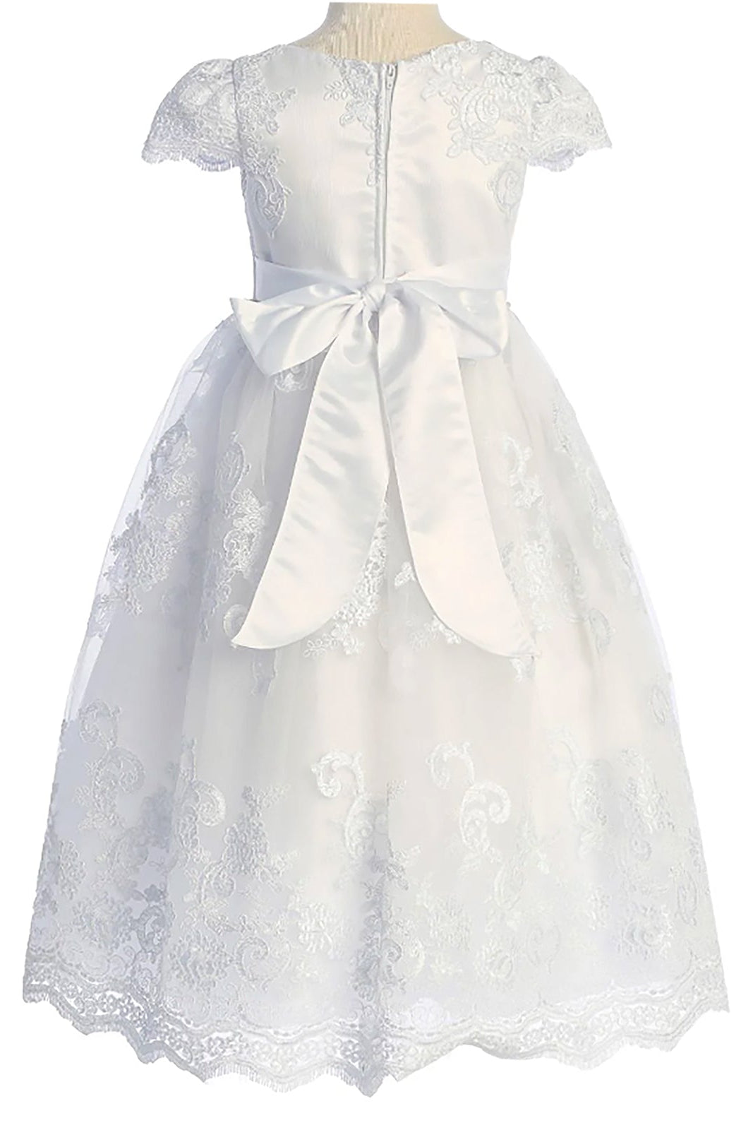 Rear view reveals white full-length communion dress with lace cap sleeves, floral lace appliques, and a satin waist bow.