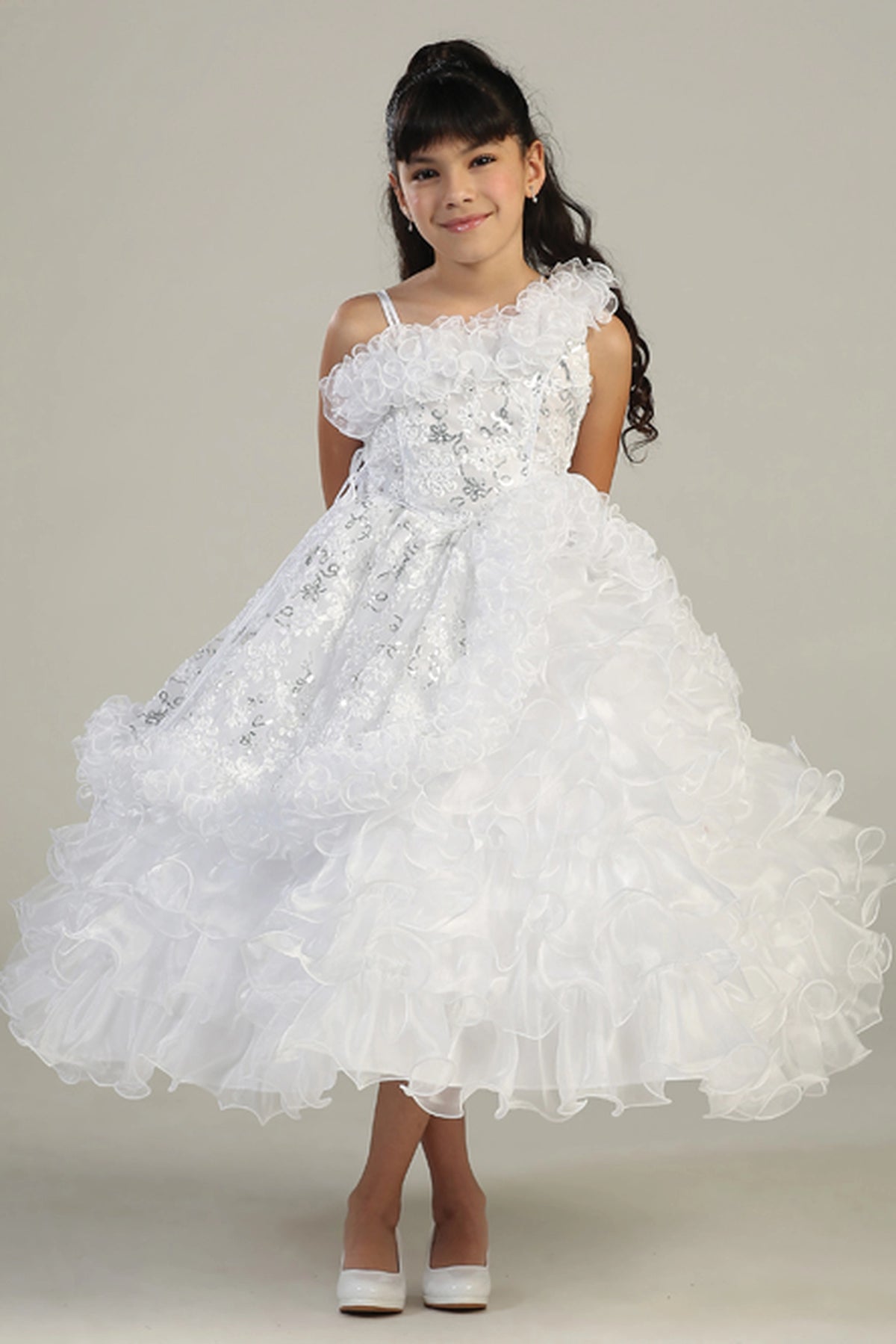 White kids pageant dress featuring an asymmetric ruffled neckline.