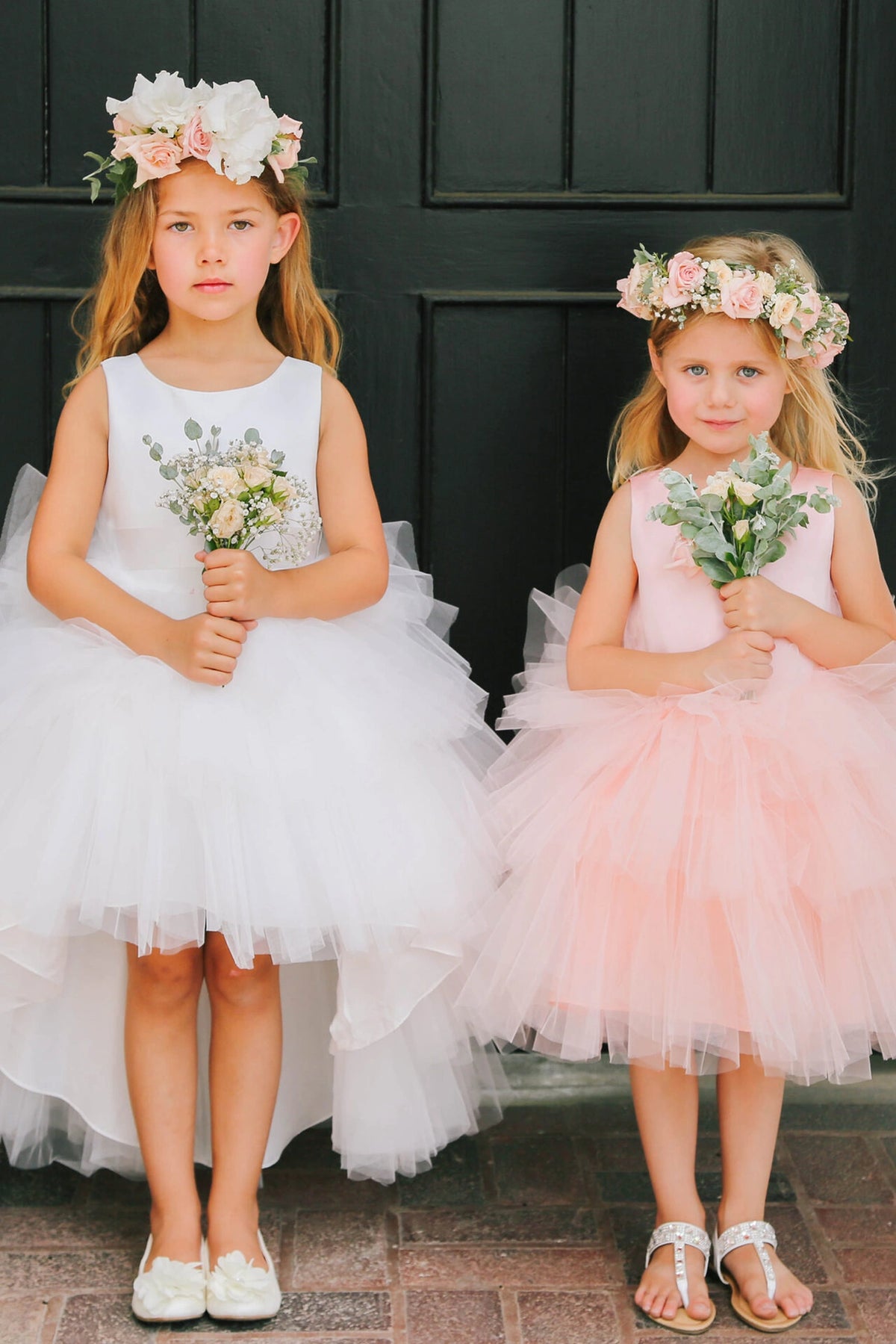 Paired White and Blush kids pageant dresses have satin bodices and layered high-low tulle skirts.