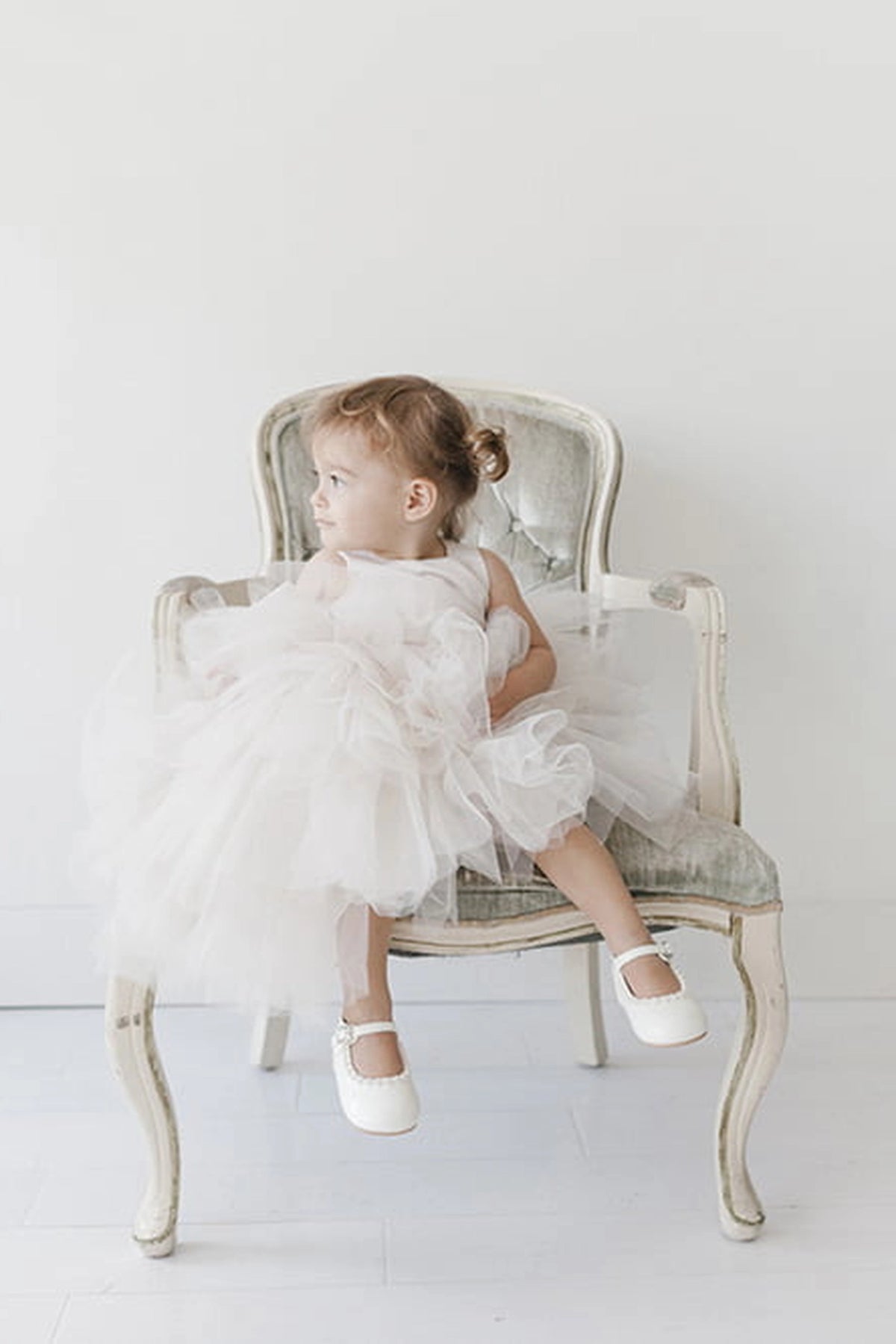 Seen from the front, this Ivory kids pageant dress displays a satin bodice and layered high-low tulle.