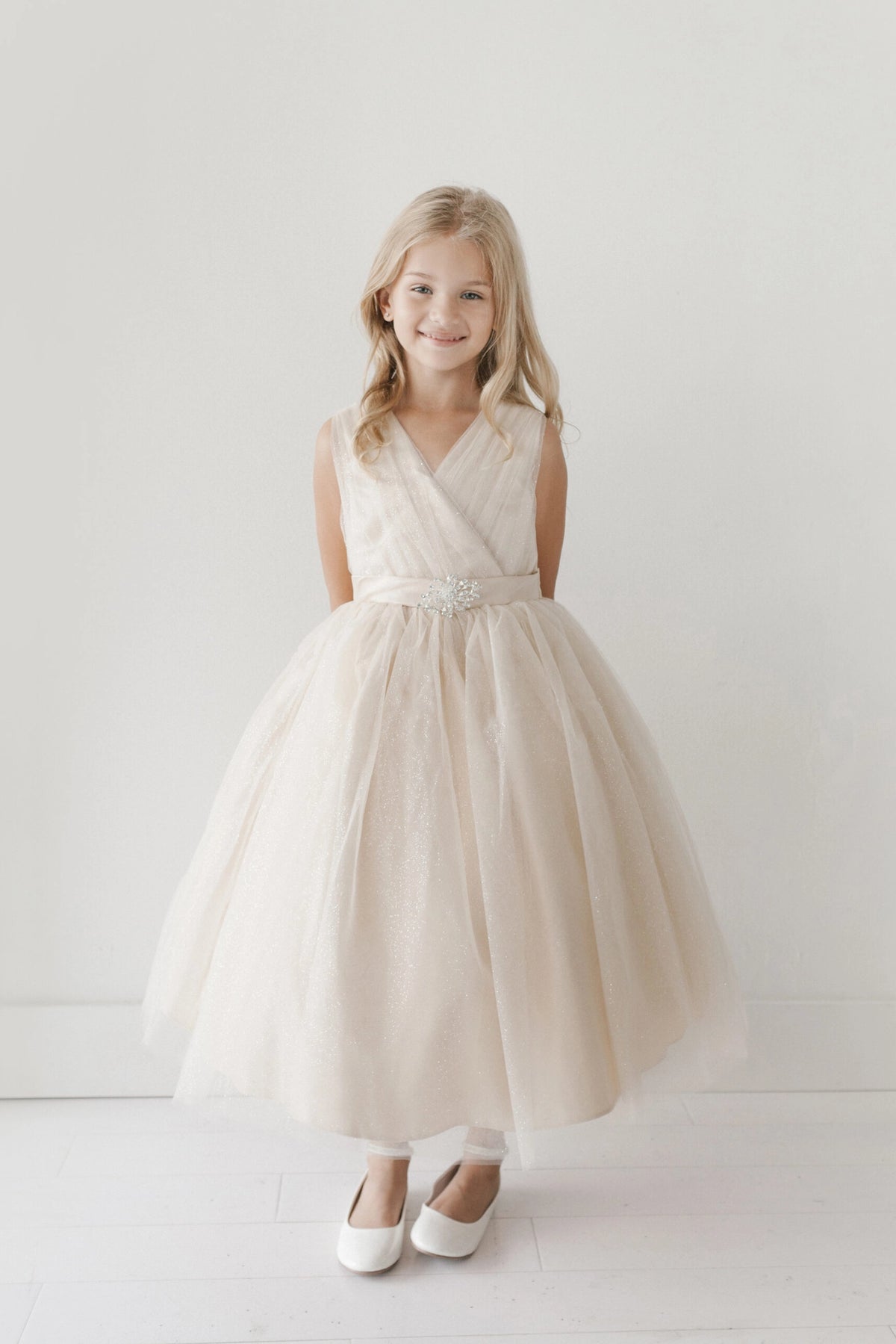 Ivory kids pageant dress featuring a ruched V-neckline and rhinestone brooch.