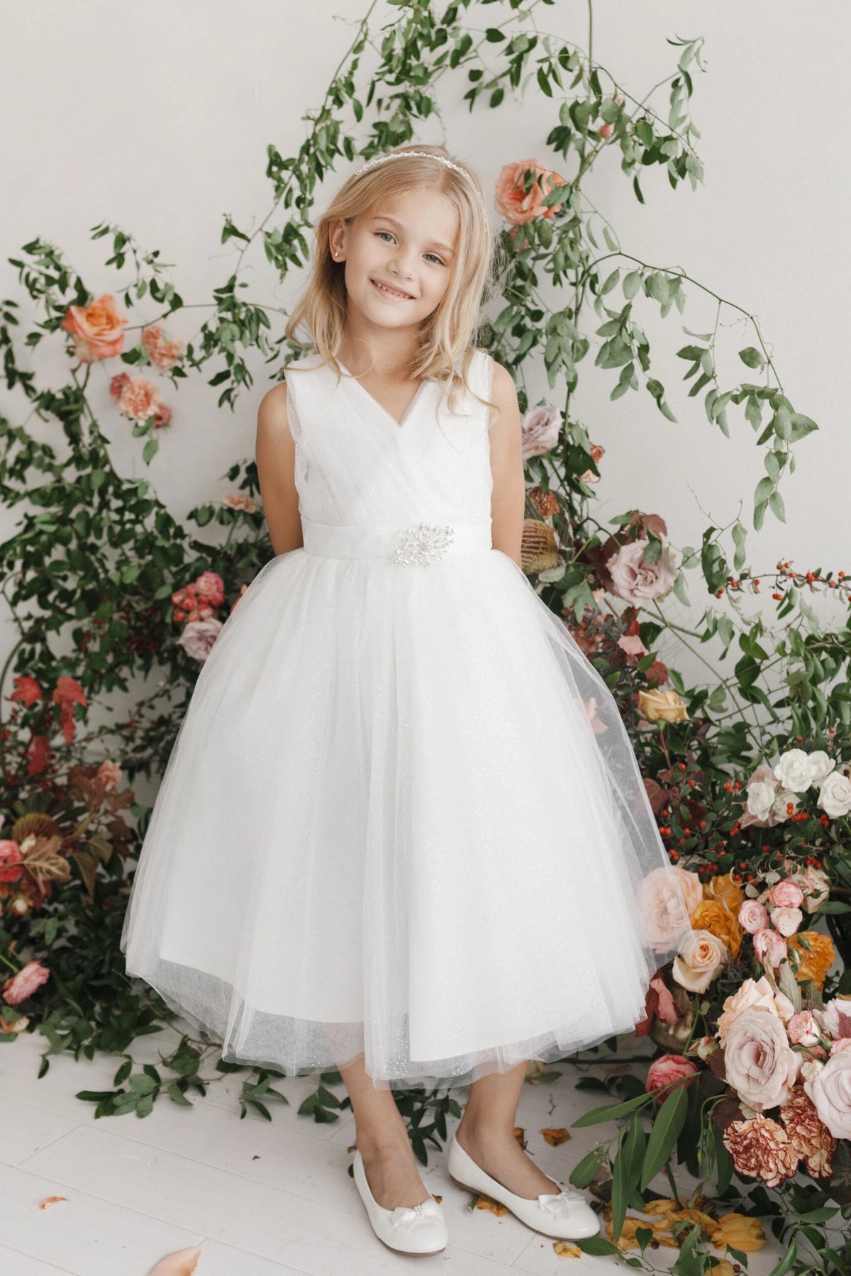 White kids pageant dress featuring a ruched V-neckline and rhinestone brooch.