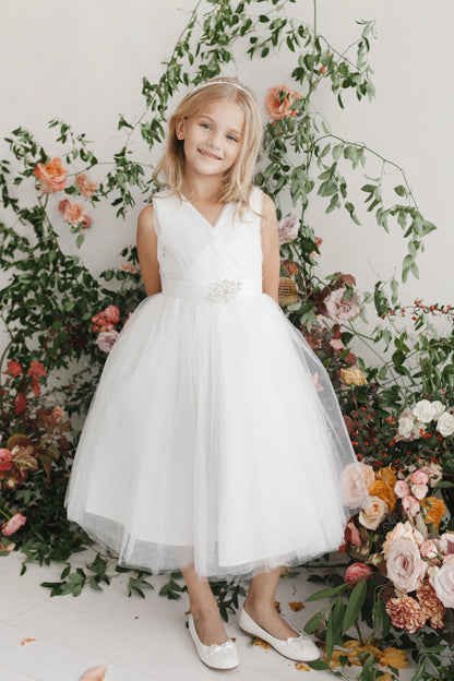 White kids pageant dress featuring a ruched V-neckline and rhinestone brooch.