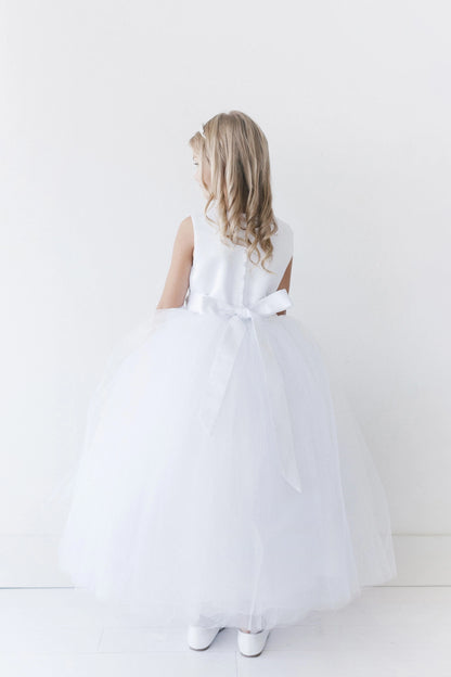 Long satin sash accents the white flower girl dress.