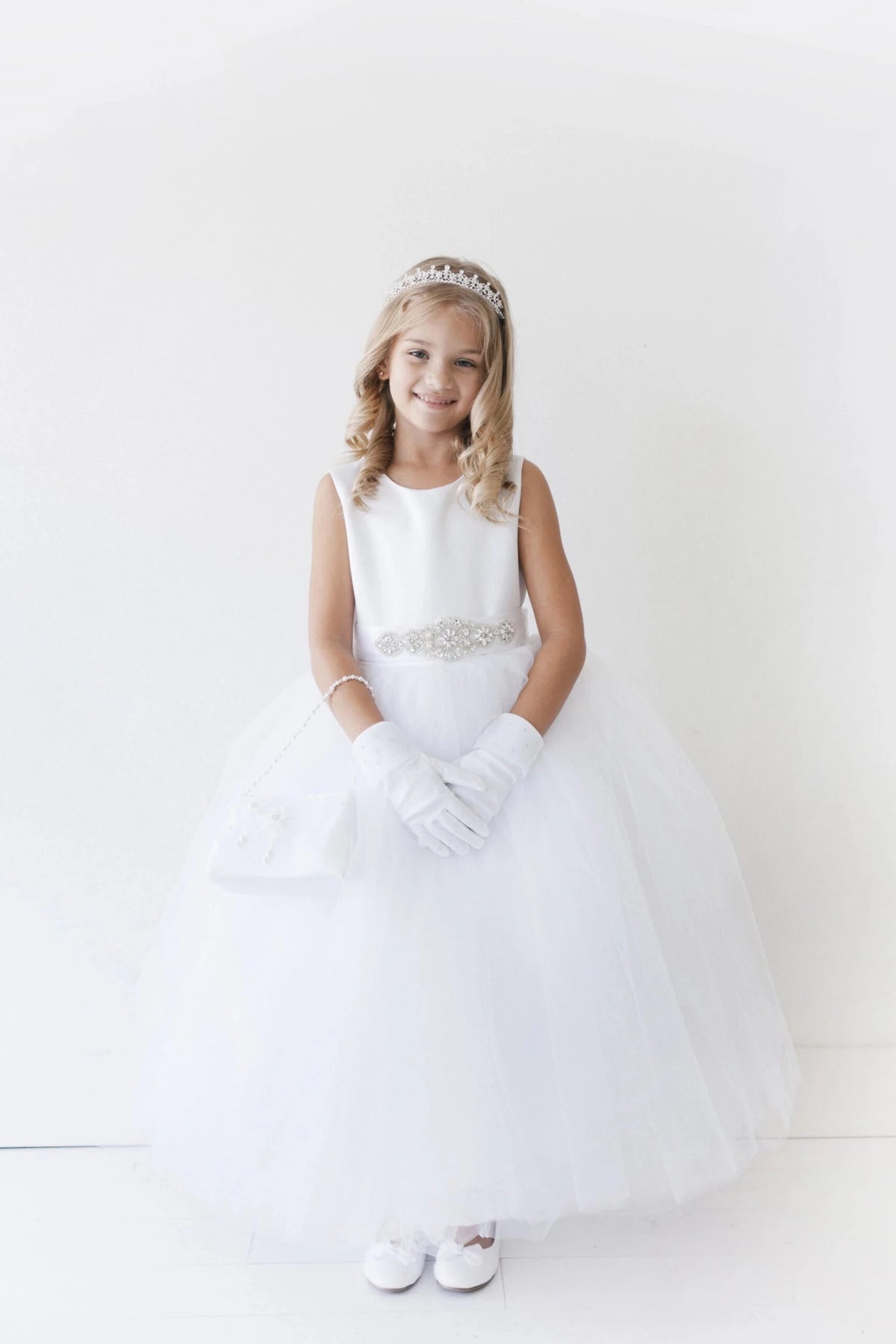 Emphasis on a smooth sleeveless bodice of the white flower girl dress.