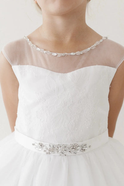 Crystal edging traces the off-white flower girl dress's sheer neckline.