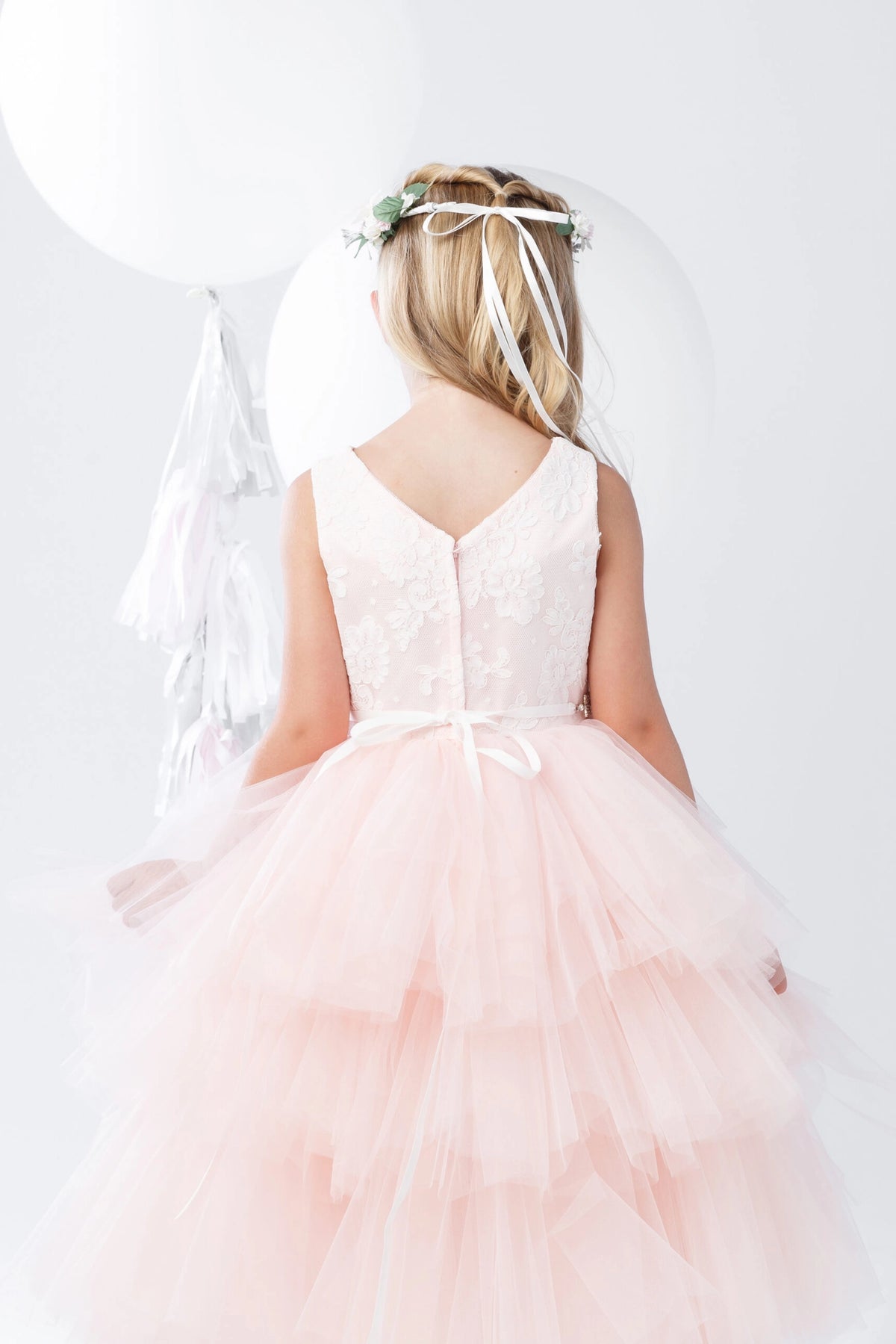 Detailed with a small back waist bow, this blush flower girl dress.
