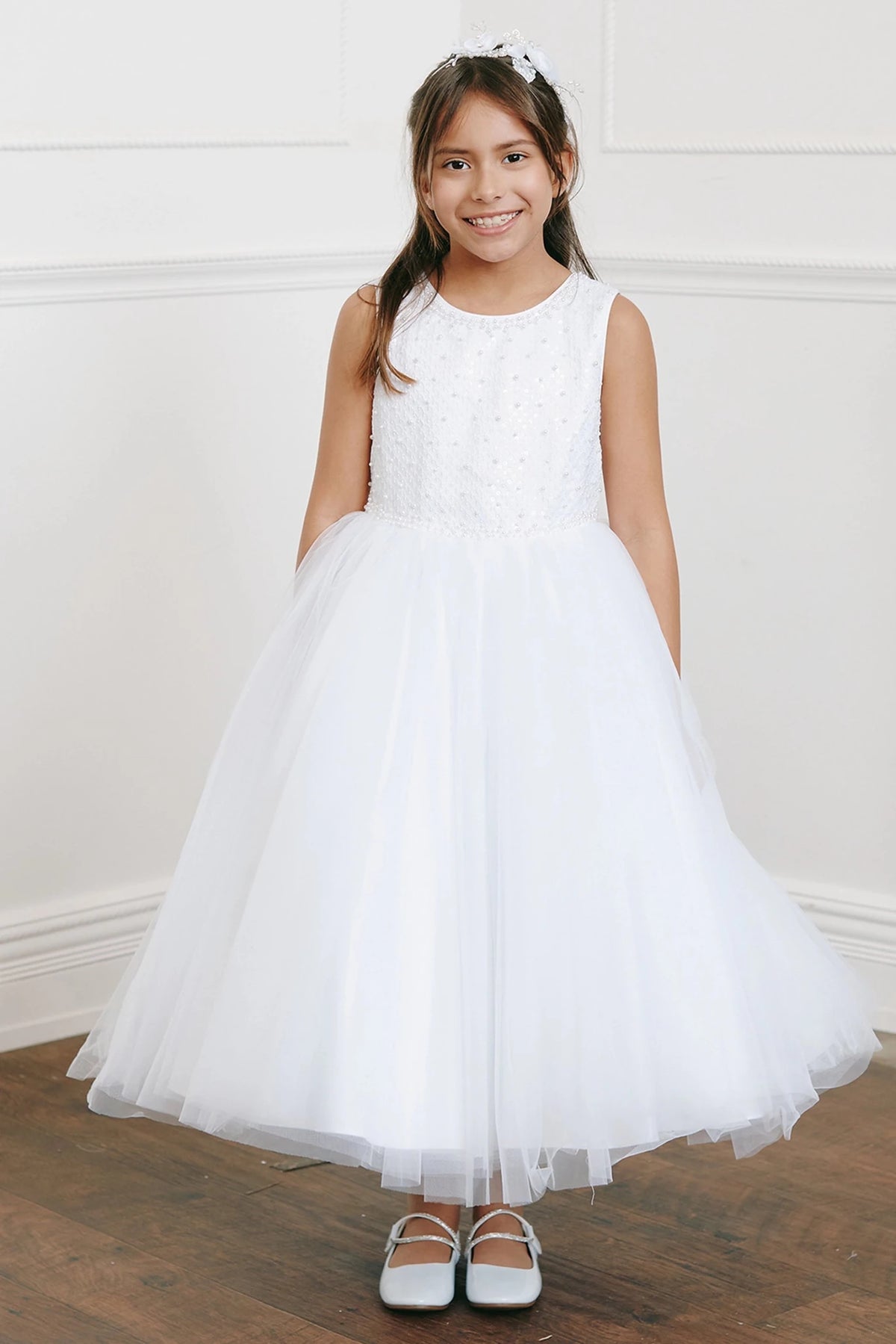 On this white flower girl dress, a beaded sleeveless bodice is visible.