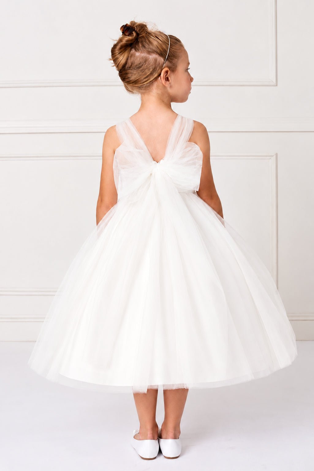 An oversized tulle bow spreads across the off-white flower girl dress's back.