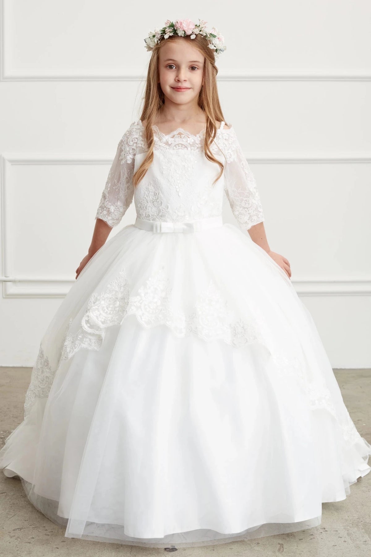 Scalloped lace forms a cascading overskirt on an off-white flower girl dress.