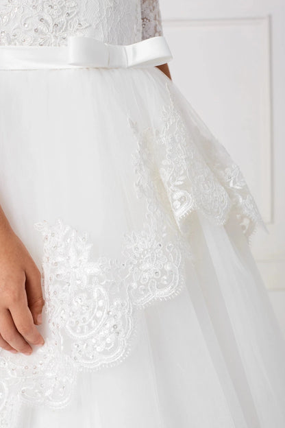 At the hip, off-white flower girl dress lace curves into pointed swags.