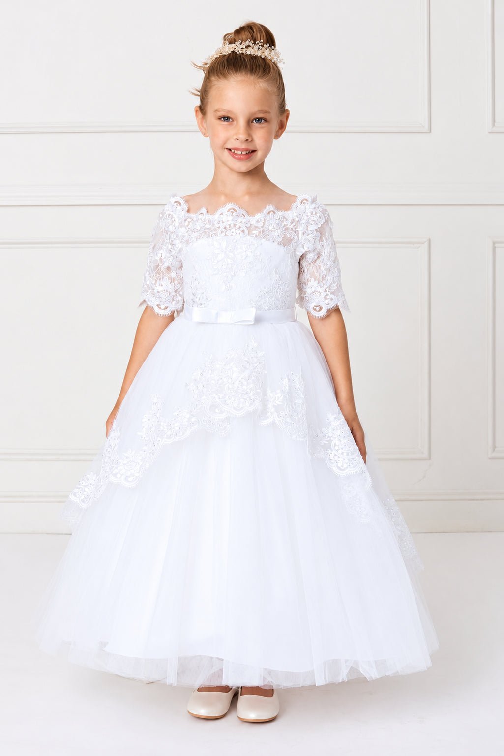 White flower girl dress edged with lace around the shoulder neckline.