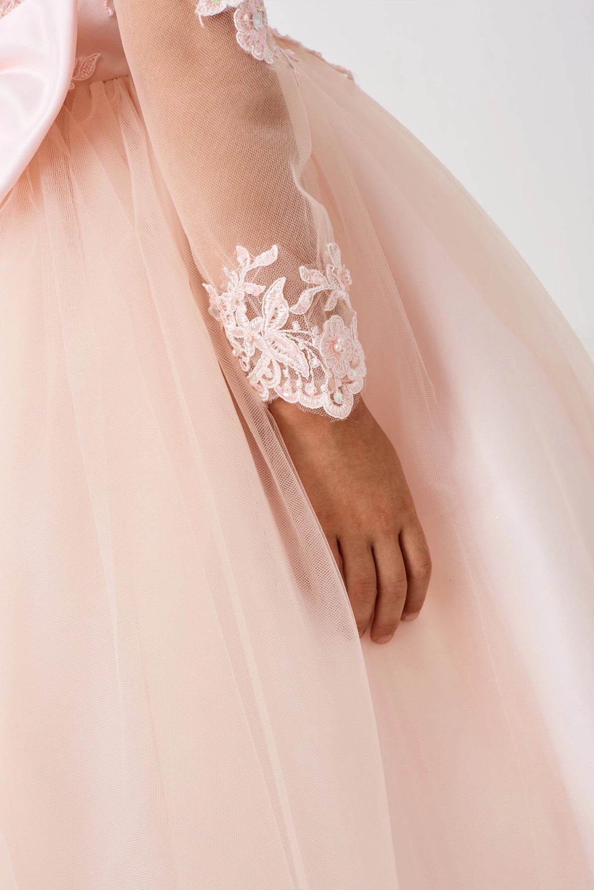 Visible details on the Blush kids pageant dress include floral lace at the sheer sleeve cuff.