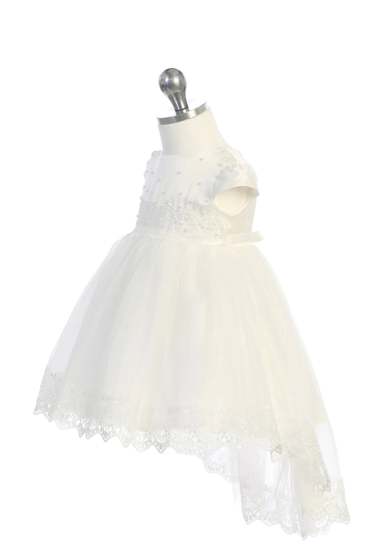Detail of the white christening dress showing lace-and-pearl waist detail and a lace-trimmed mesh skirt.