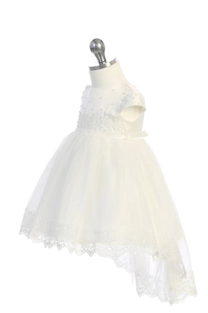 Detail of the white christening dress showing lace-and-pearl waist detail and a lace-trimmed mesh skirt.
