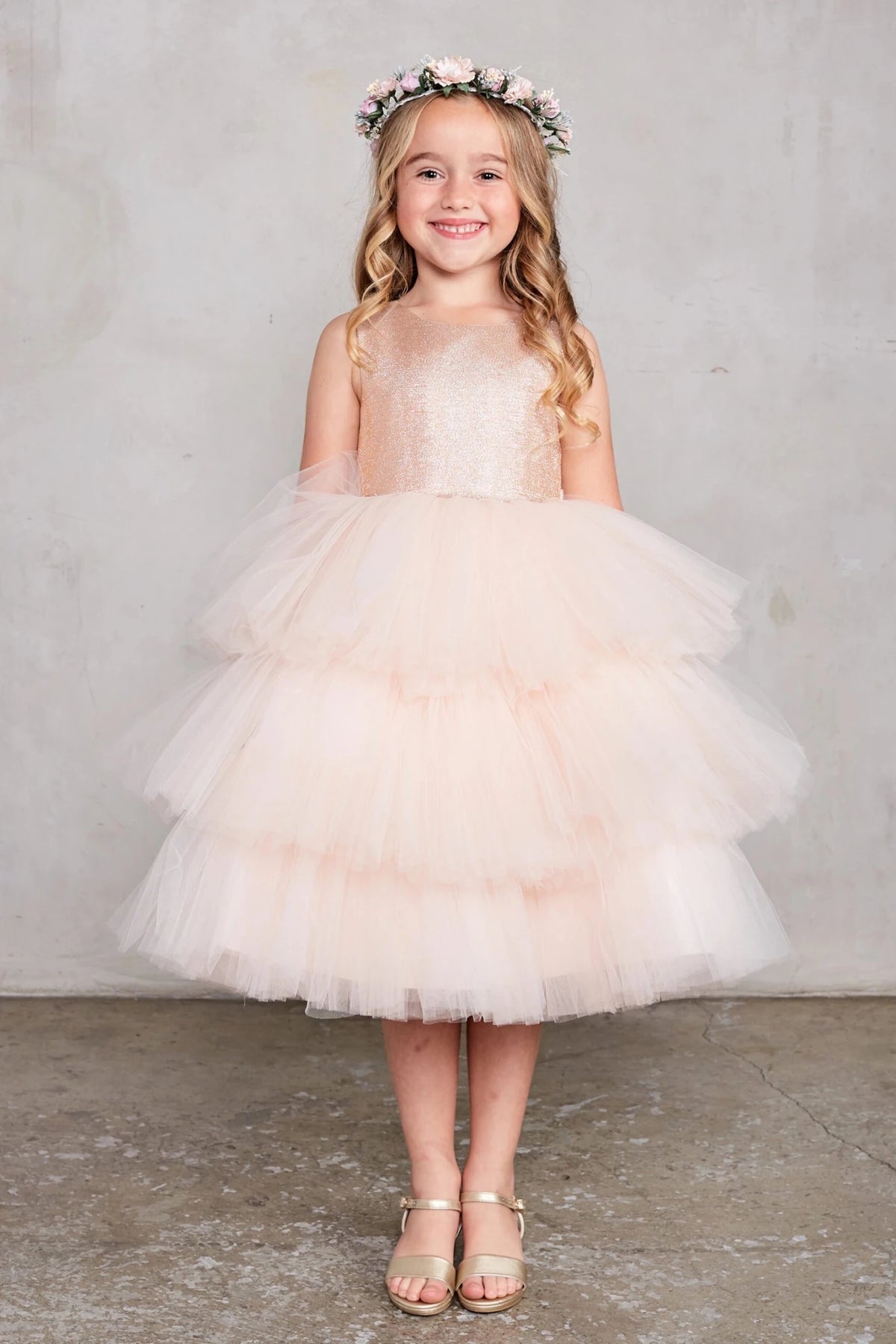 Detailed with a tiered tulle skirt, this rose gold flower girl dress.
