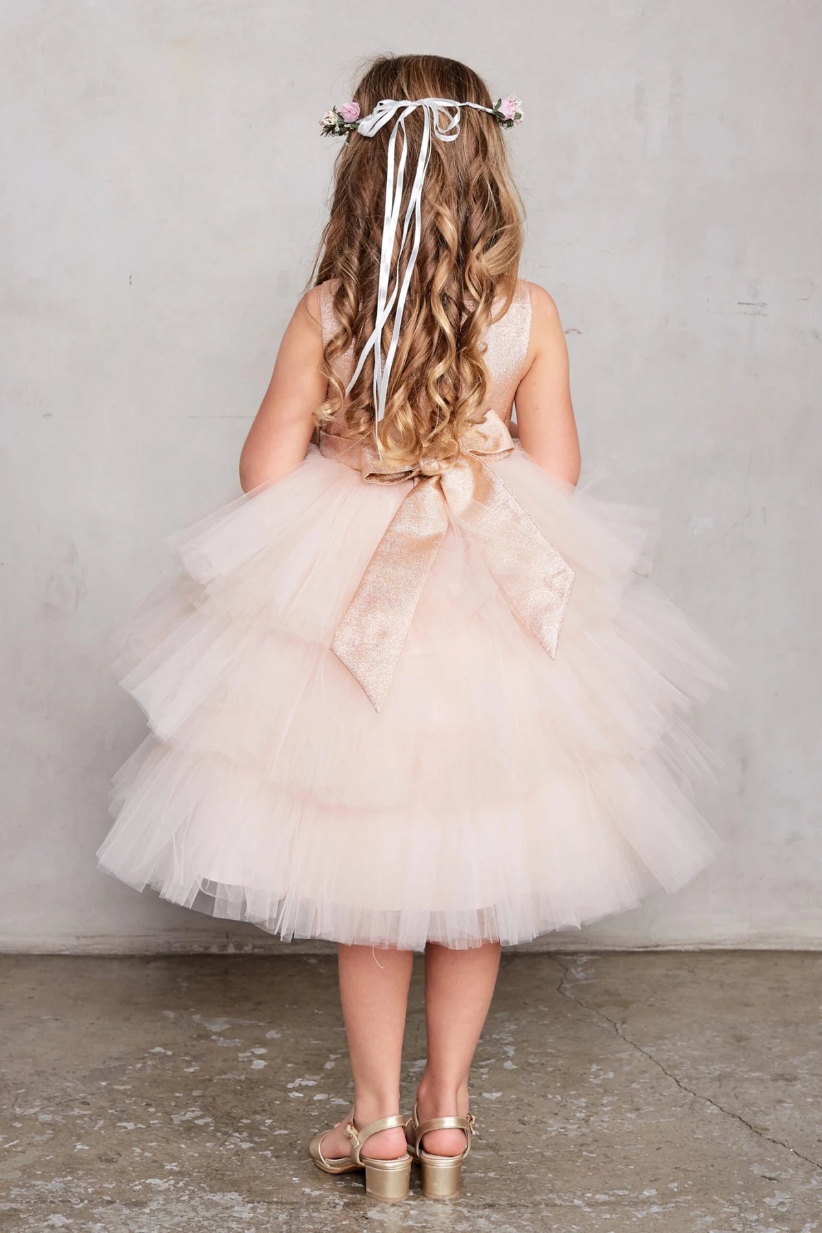 Featuring a large satin back bow, a rose gold flower girl dress.