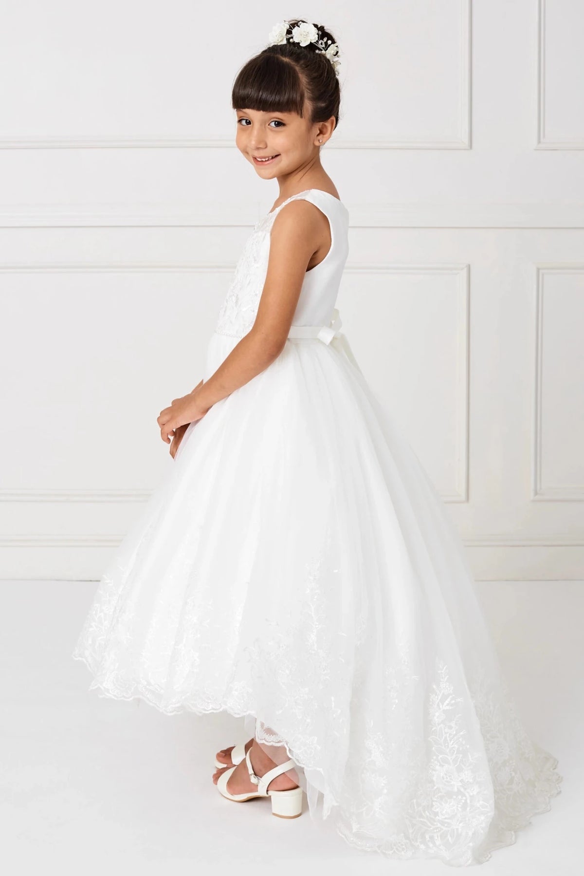 Longer at the back, the off-white flower girl dress has a scalloped lace hem.