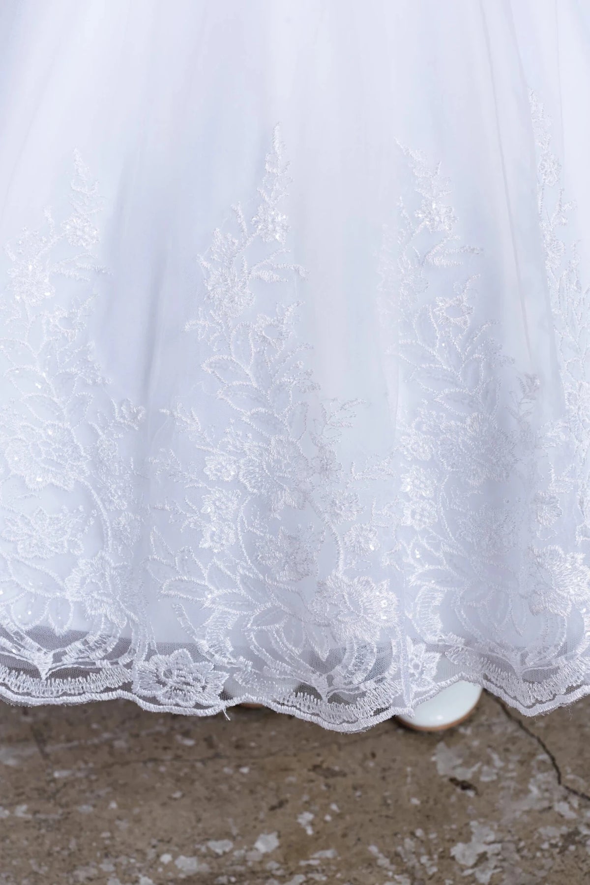 Shown here, a white flower girl dress with a scalloped embroidered hem.