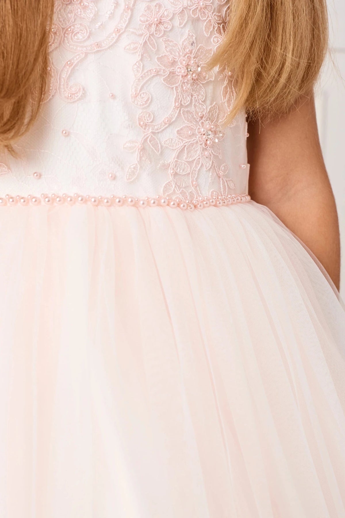 Pink beads trace the waistline of this blush flower girl dress.