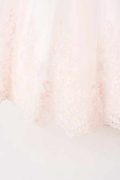 Vine-shaped lace rises from the blush flower girl dress's hem.