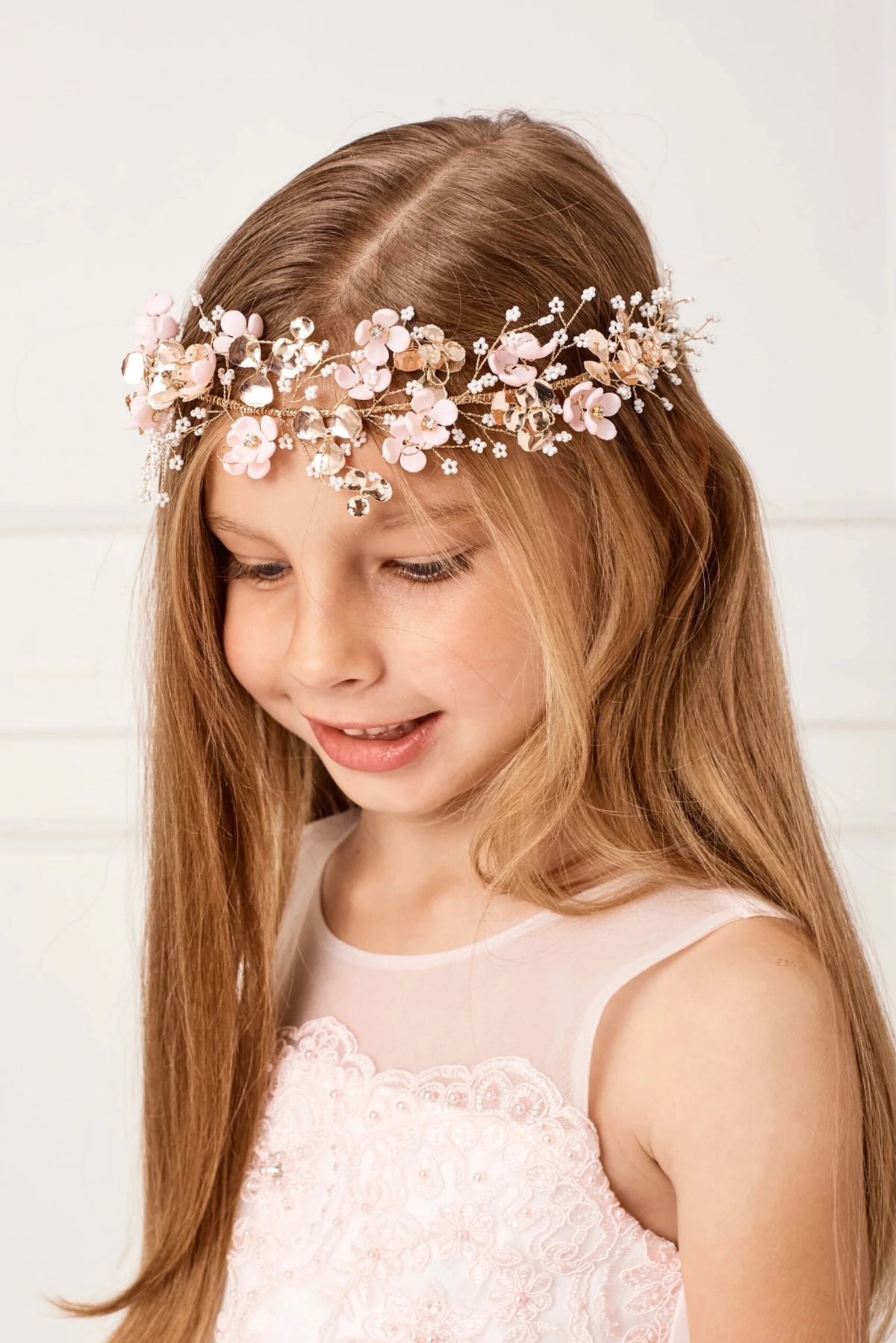 Sheer fabric softens the round neckline of a blush flower girl dress.