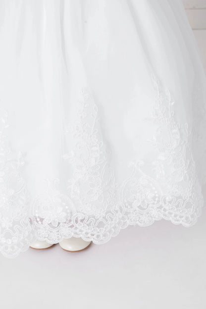 Along the edge, the off-white flower girl dress has leafy lace scallops.