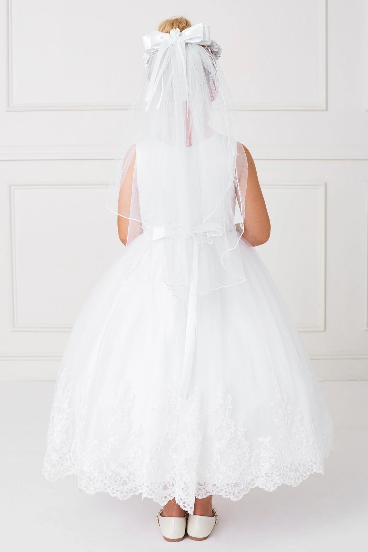 Trailing floral lace outlines the off-white flower girl dress's back hem.