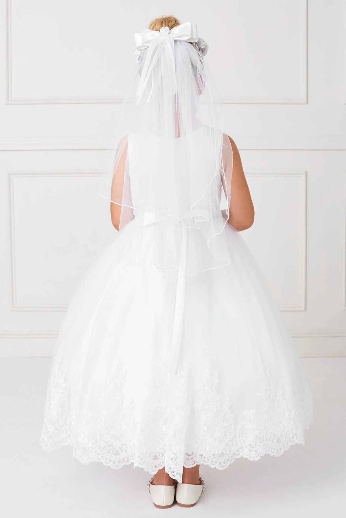Trailing floral lace outlines the off-white flower girl dress's back hem.
