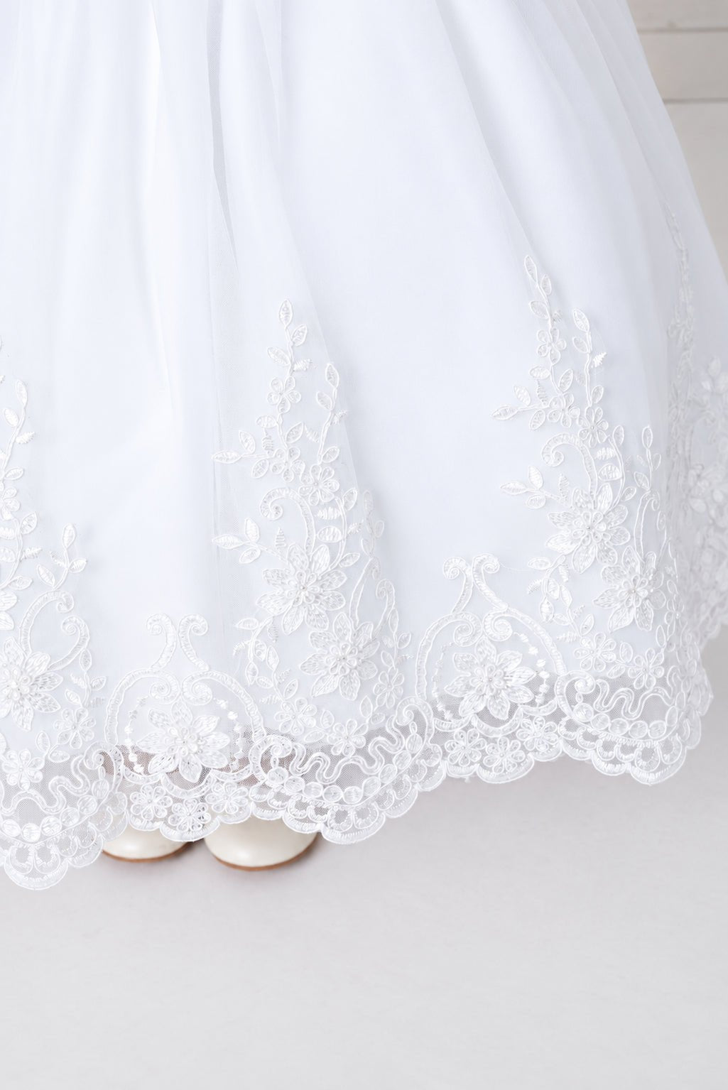 Looped lace scallops edge the white flower girl dress's hem.