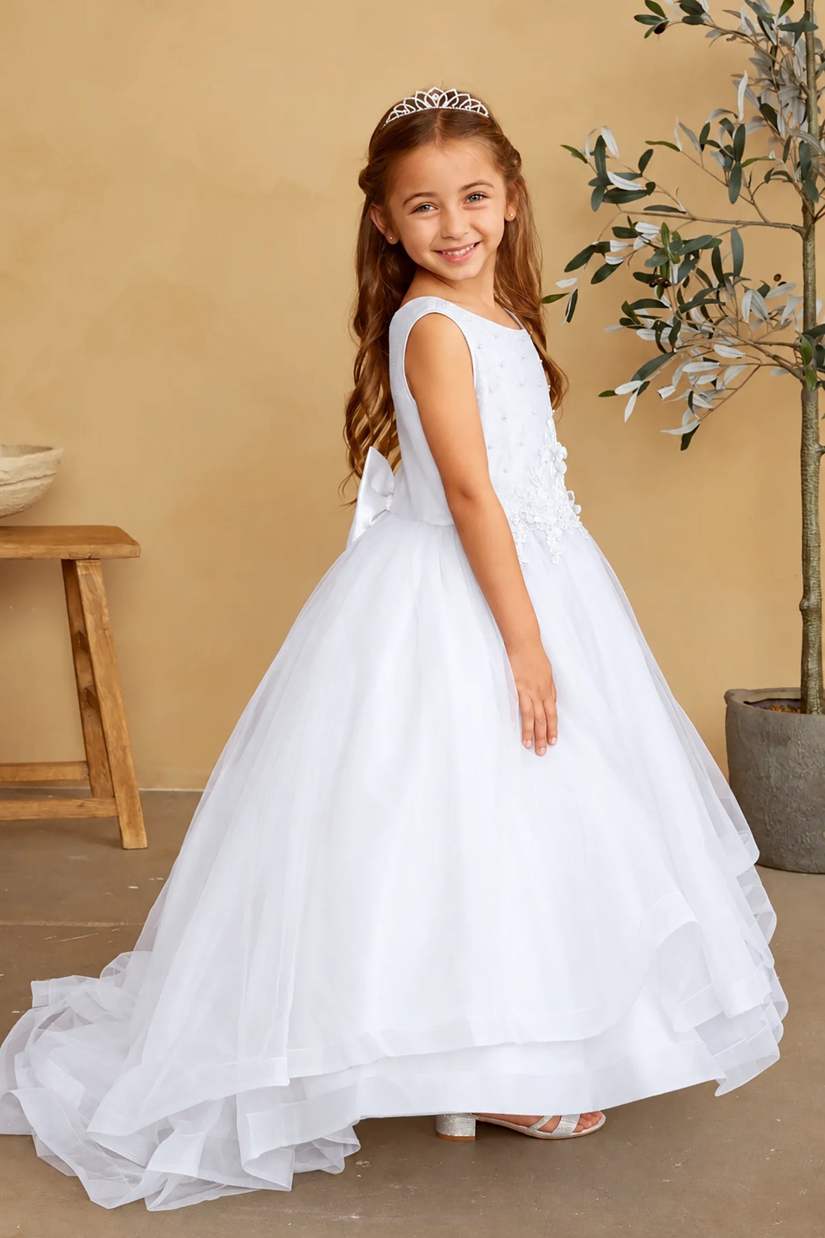 Sweeping behind the white flower girl dress is a layered tulle train.