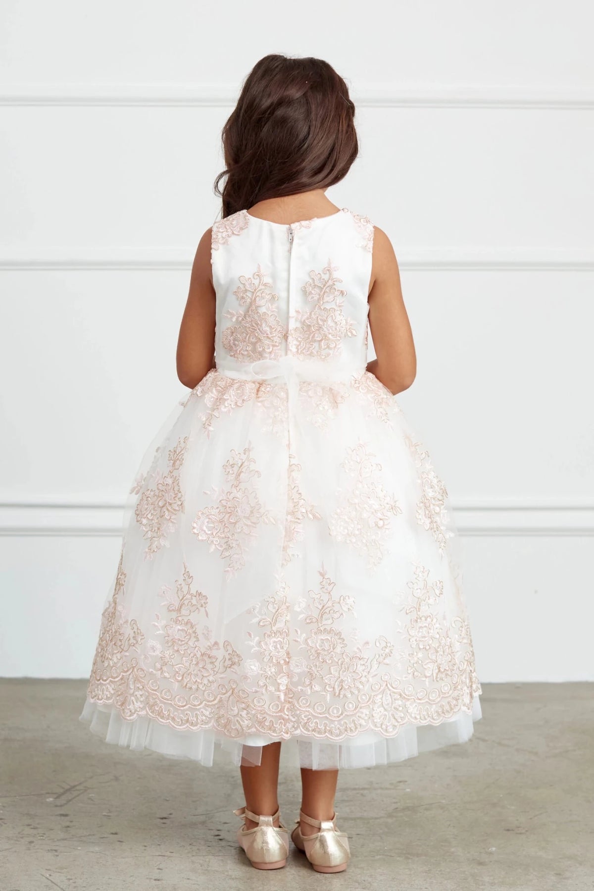 This blush flower girl dress displays sheer floral back.