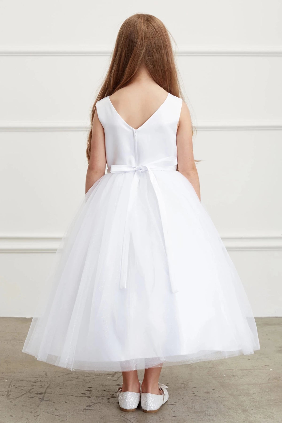 In view: a V-shaped back neckline of a white flower girl dress.