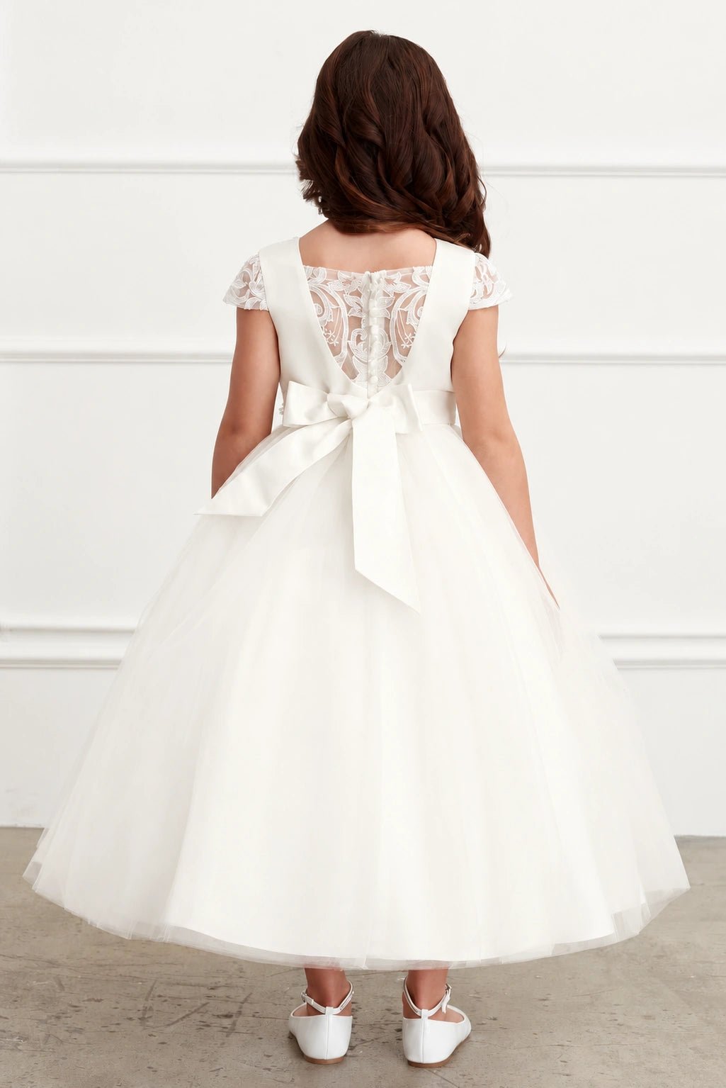 Highlighting an oversized satin back bow on an off-white flower girl dress.