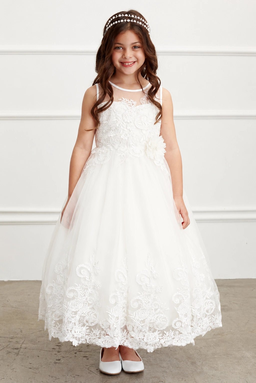 A view of a swirling lace hem on the off-white flower girl dress.