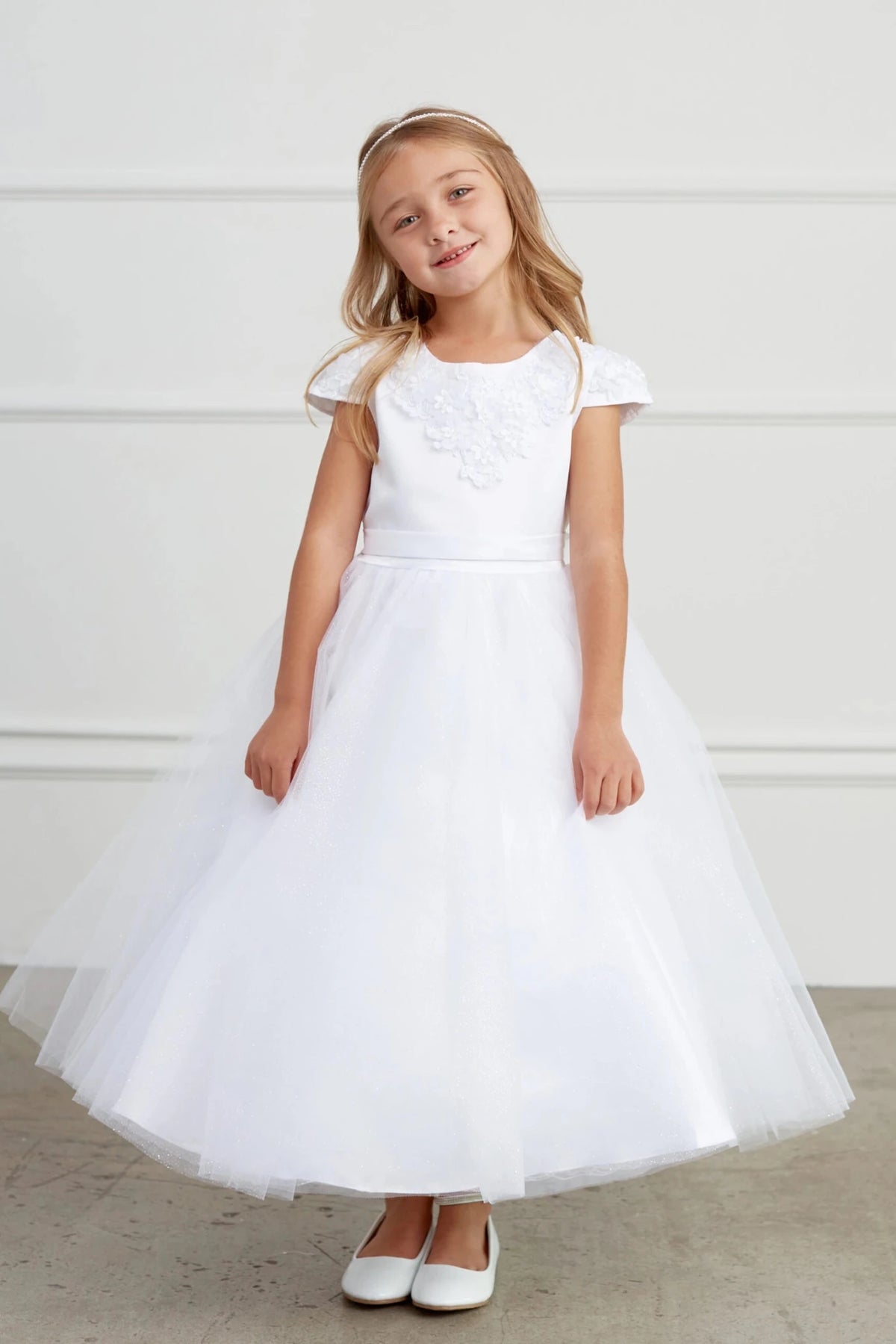 The white flower girl dress features embroidered cap sleeves.