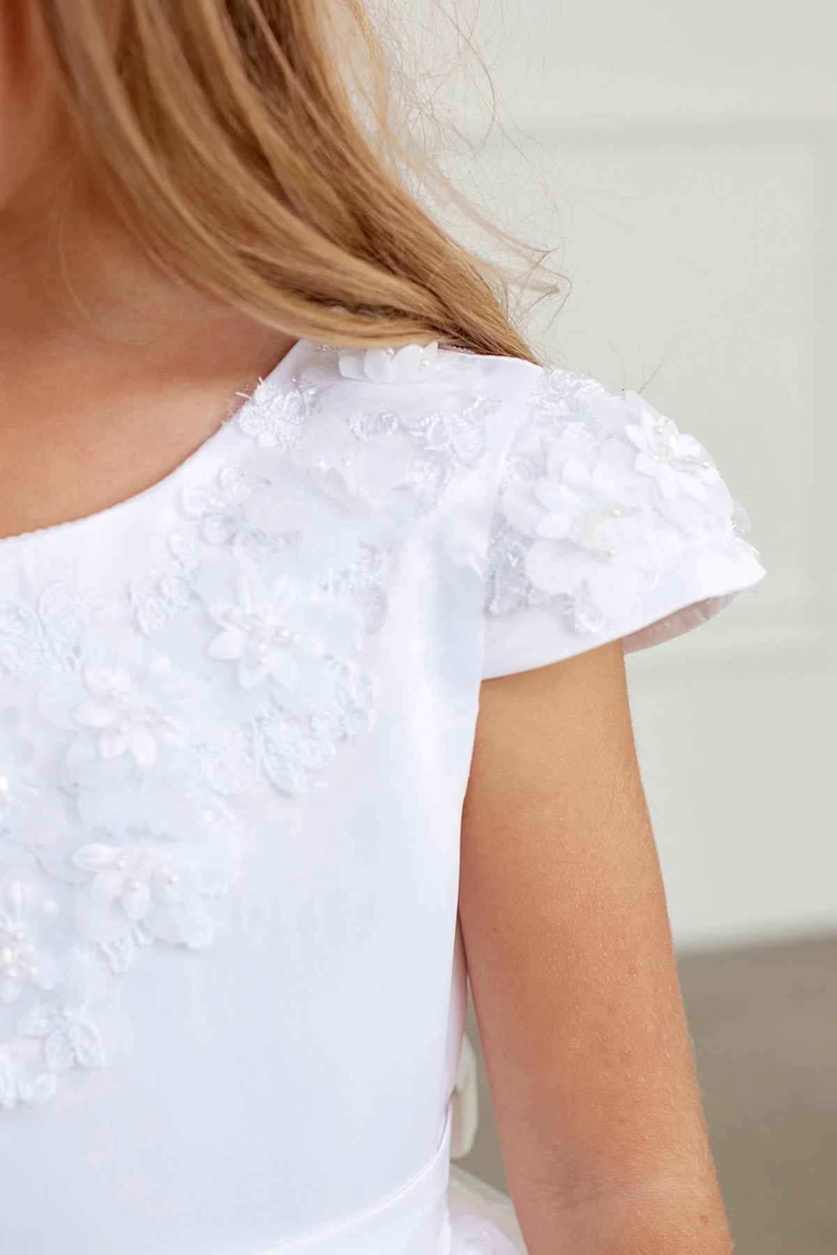 On this white flower girl dress, 3D flower shoulder trim is visible.