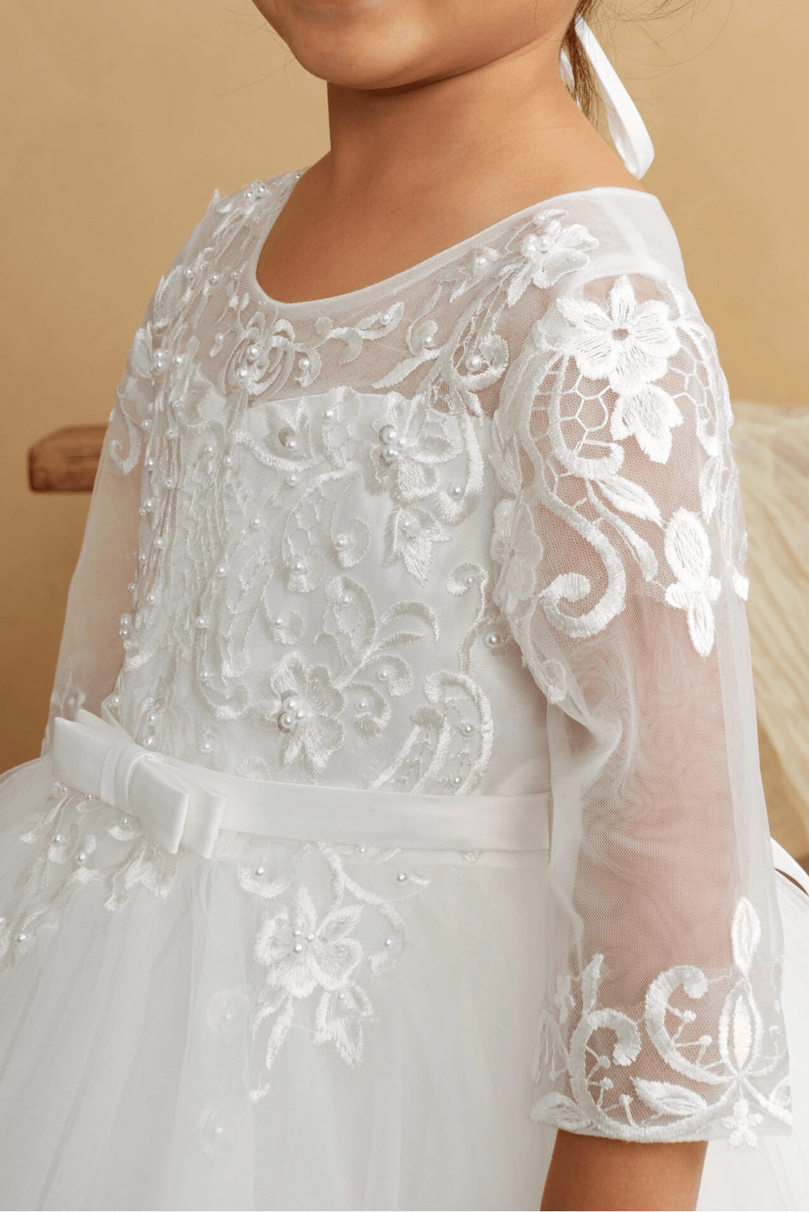 Close-up of the ivory illusion lace with sheer sleeves flower girl dress.